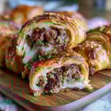 Mini pigs in a blanket with dipping sauce served on a white platter, golden pastry-wrapped sausages glistening with egg wash.