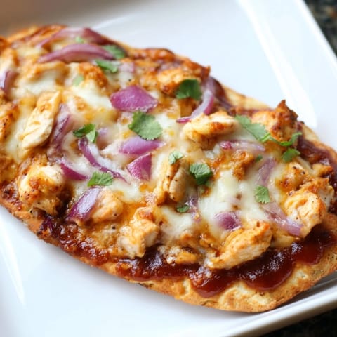 A close-up of BBQ Chicken Flatbread showing gooey, stretchy mozzarella and tangy BBQ sauce drizzled over tender chicken and sweet onions.  