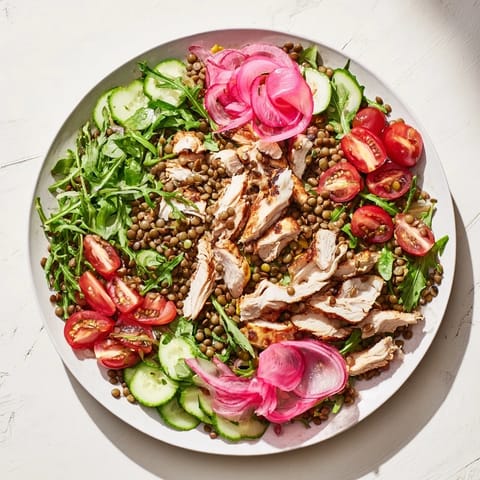 A vibrant bowl of Lentil & Chicken Spring Salad topped with cherry tomatoes and cucumber slices for a refreshing lunch.