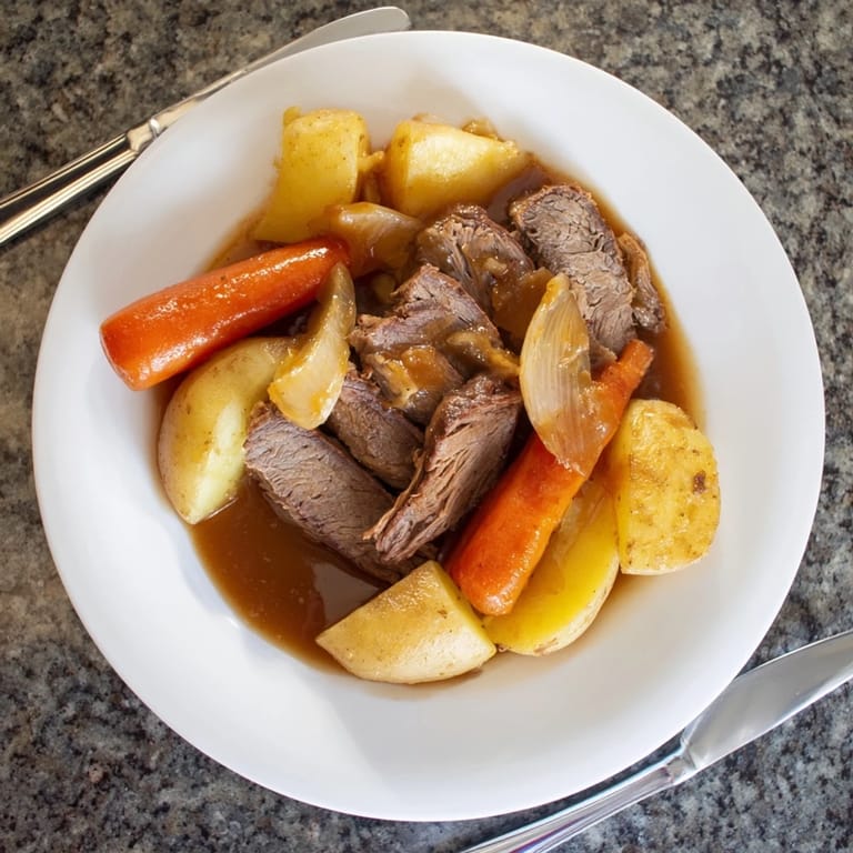 A rustic wooden table displays a bubbling Beef Pot Roast, surrounded by carrots, potatoes, and a glass of red wine.