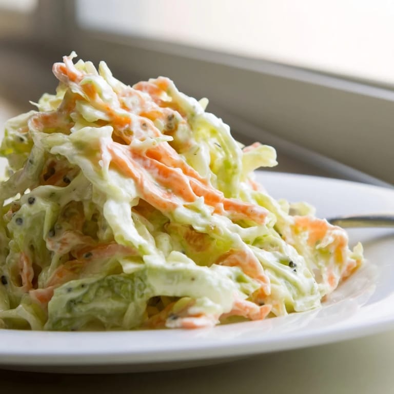 Hearty Coleslaw piled high in a serving bowl, chilled and tossed, ideal for picnics or sandwiches.