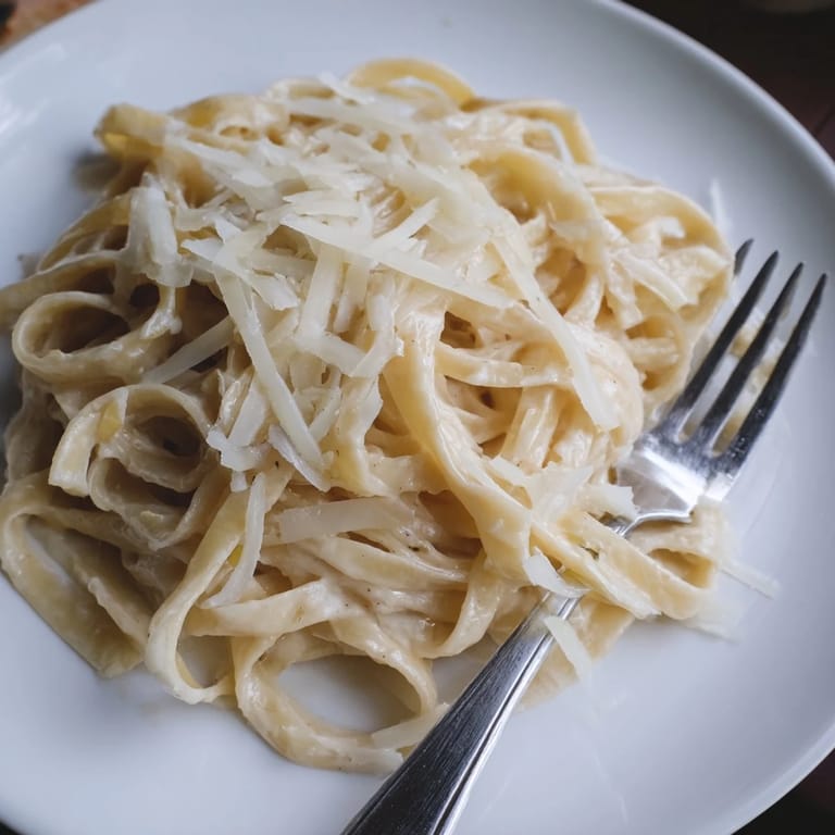 Freshly grated Parmesan garnishes this comforting Roasted Garlic Cream Pasta, highlighting the rich, velvety texture of the homemade Italian sauce.