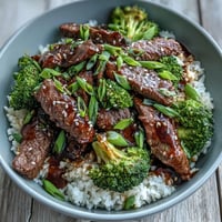 Steamed broccoli florets and tender beef strips in a soy-ginger sauce top fluffy white rice in this Beef and Broccoli Bowl.